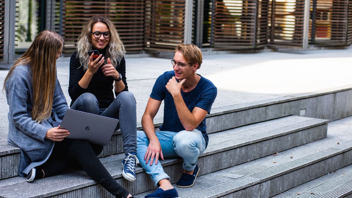 three college students sitting on steps outside of a building