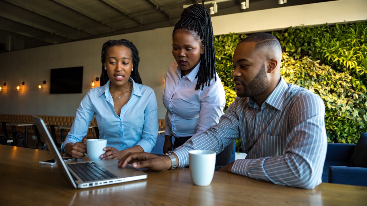 three writers standing at a laptop