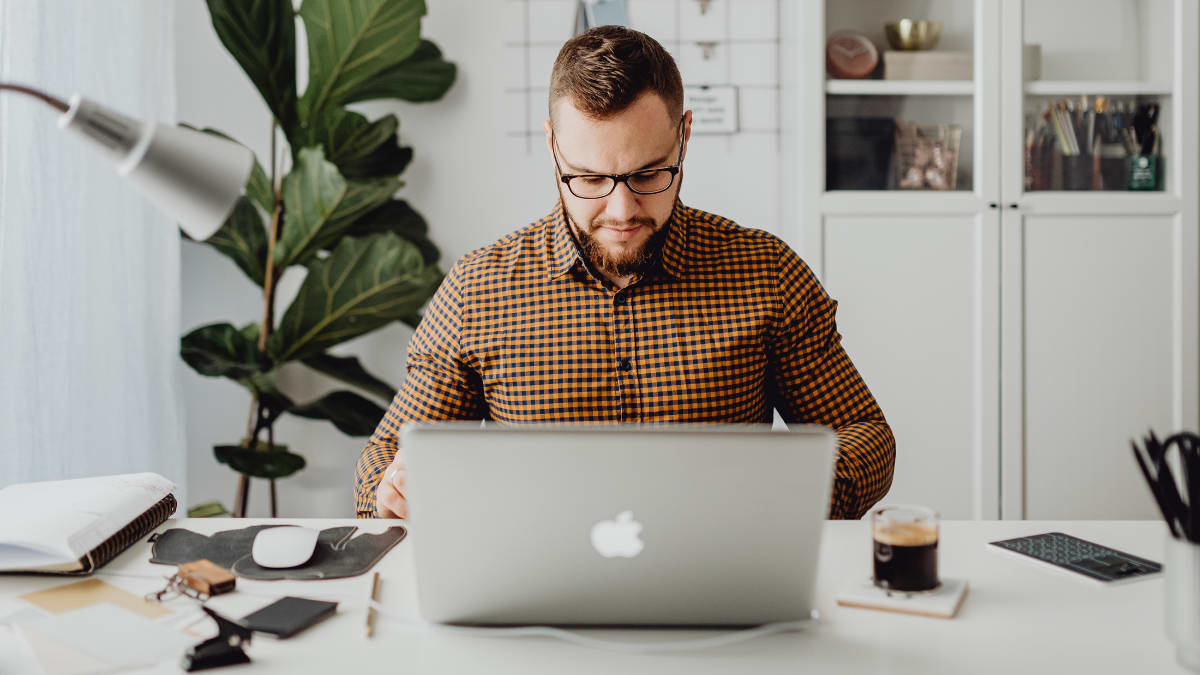 author sitting at a desk typing on a laptop