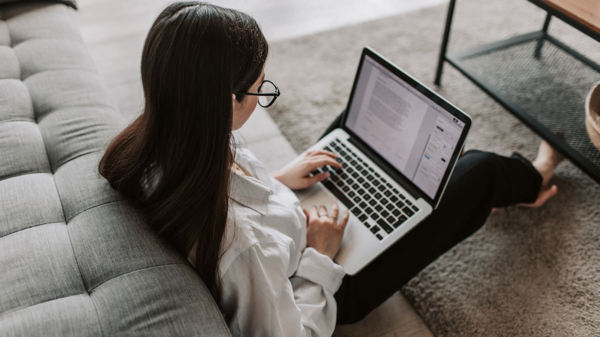 author sitting on the floor typing on a laptop