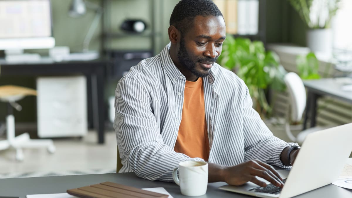 author sitting at desk typing on a laptop