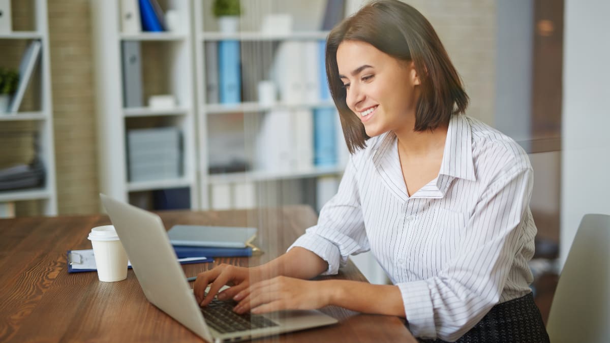 author sitting at a desk typing on a laptop