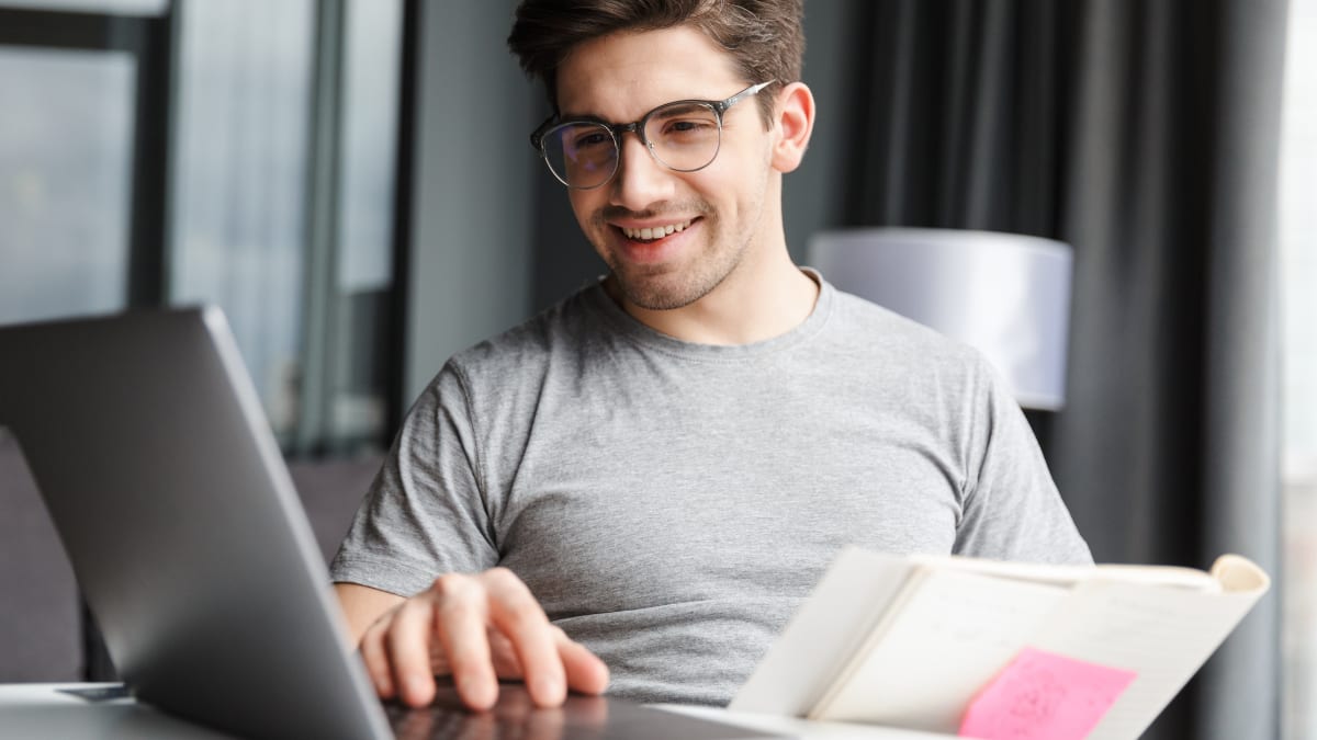 author sitting at a desk typing on a laptop