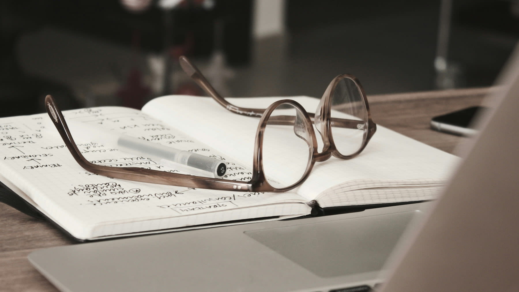Eyeglasses and pen on top of an opened notebook