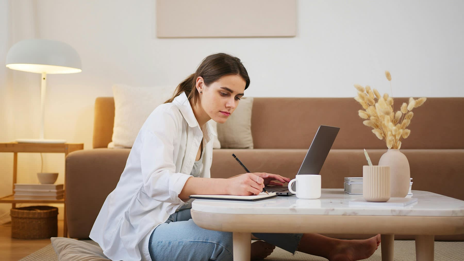 Woman taking notes while using her laptop