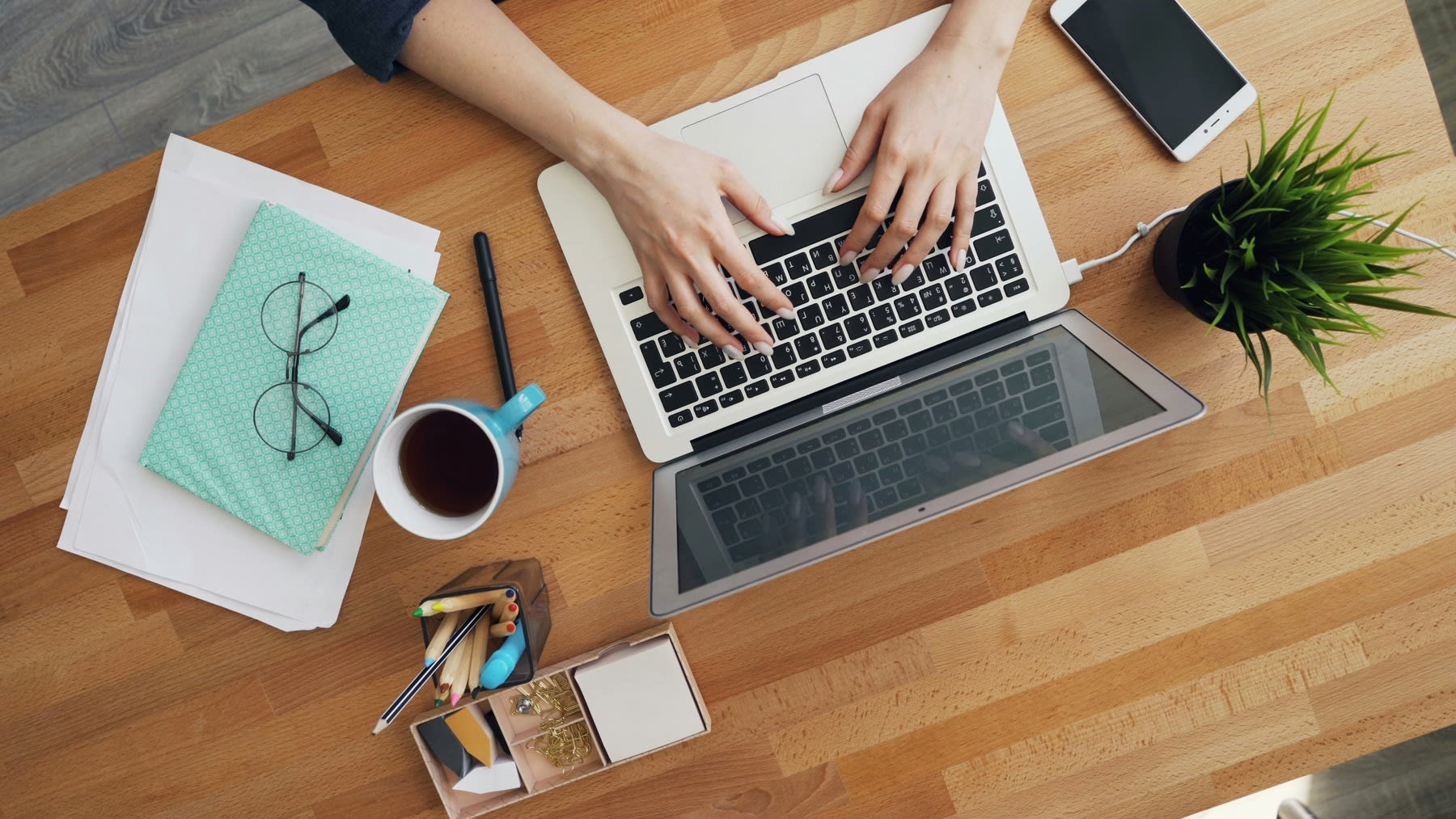 Person using a laptop on a wooden table