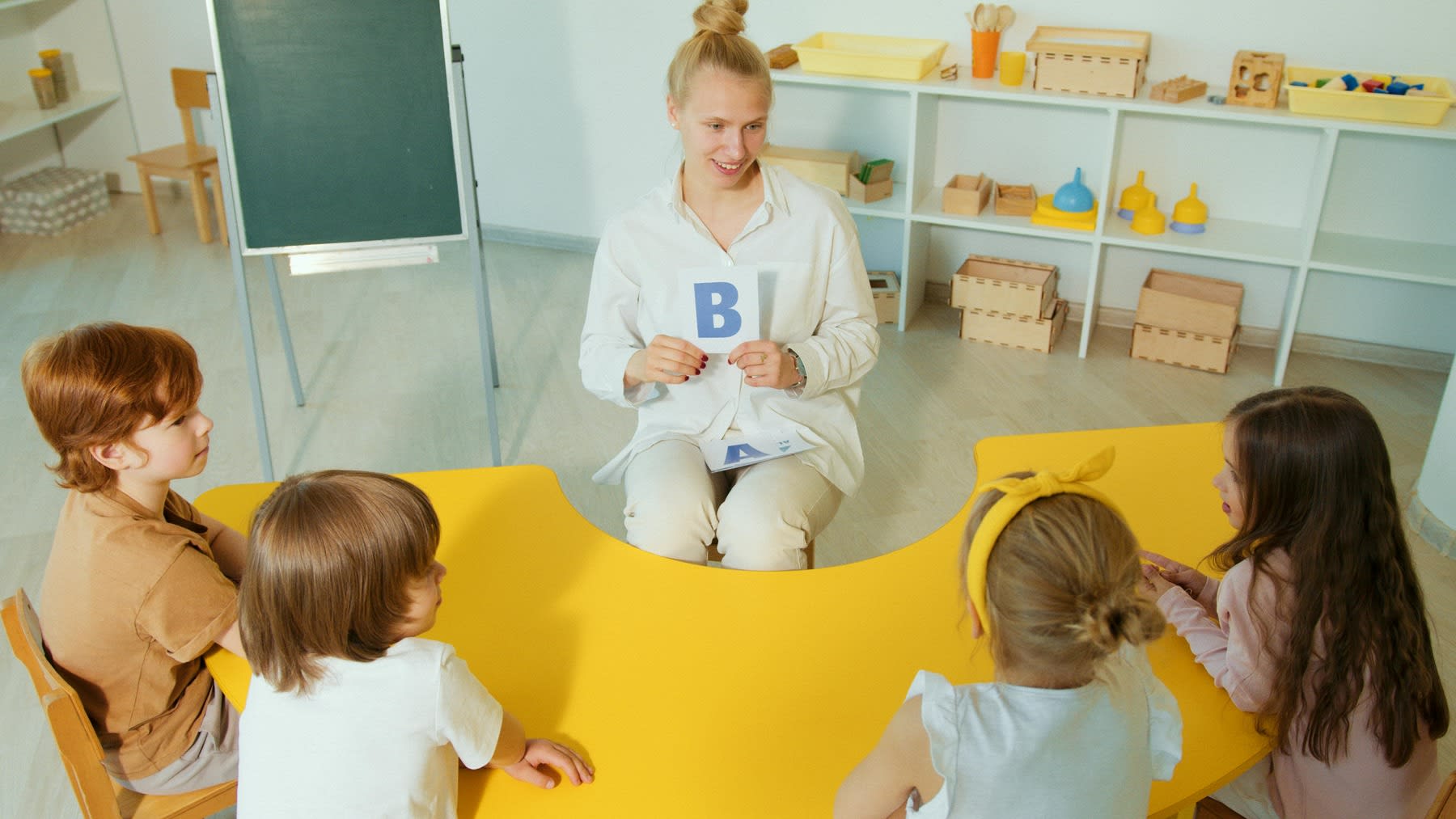 Woman holding a letter flashcard to her kindergarten class