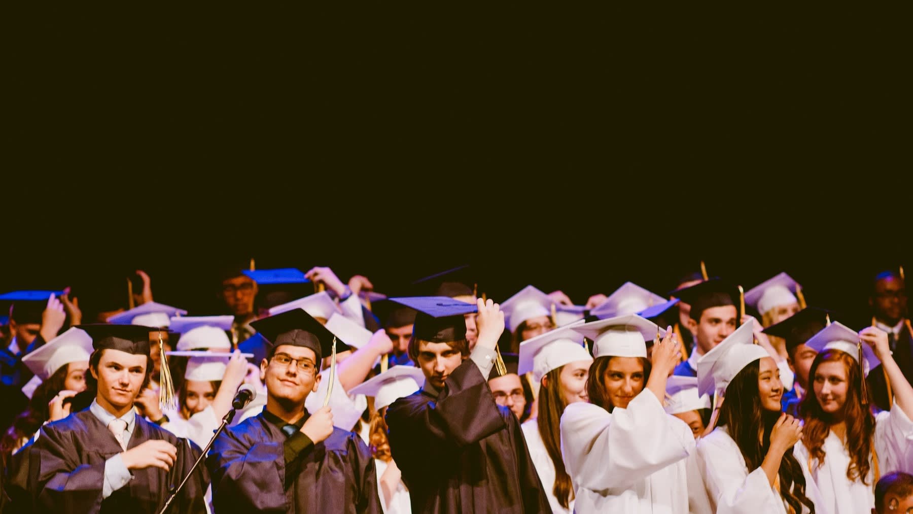 Students wearing their graduation robes while all holding their graduation caps