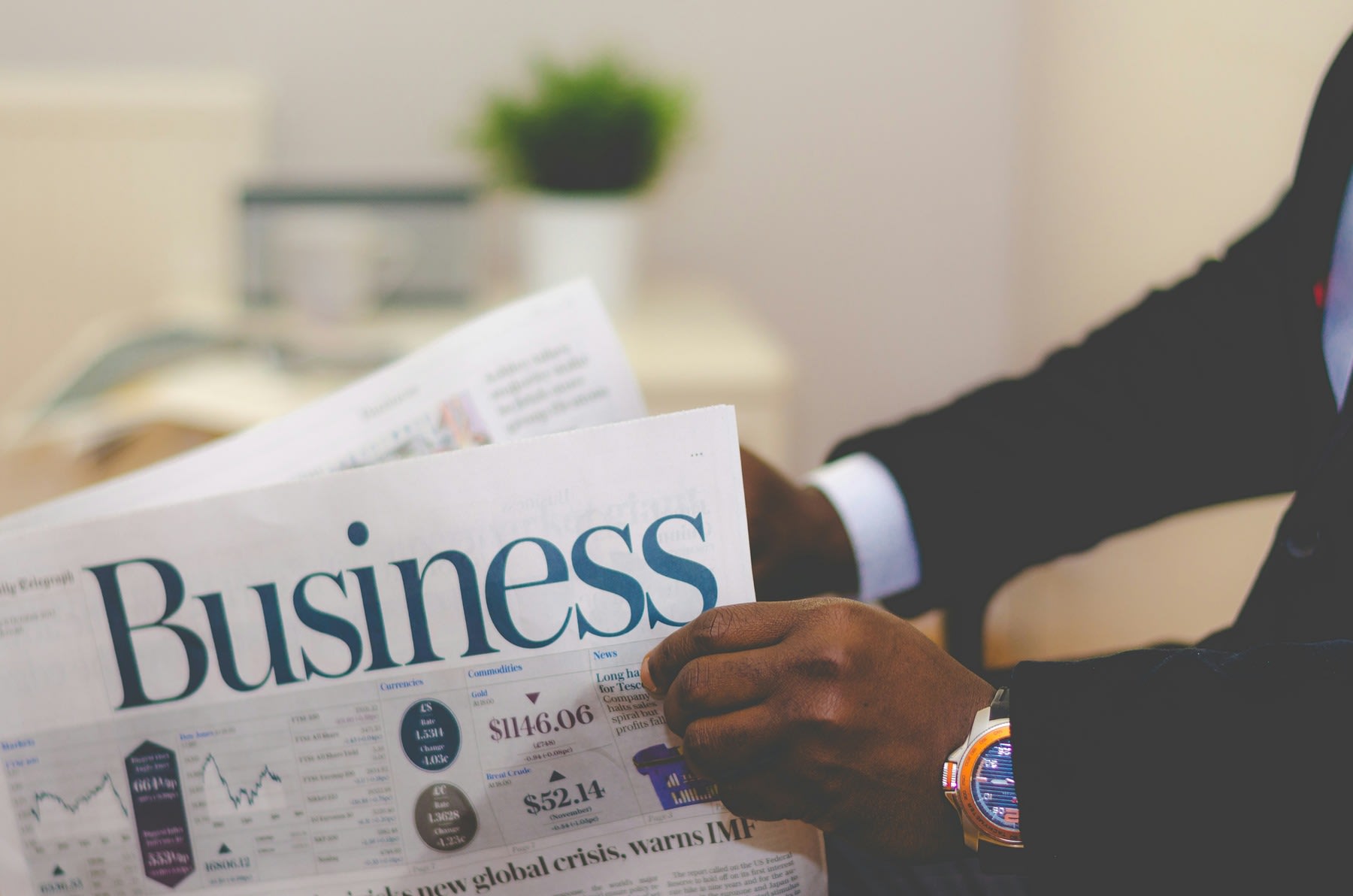 Man wearing a suit, reading the business section of a newspaper