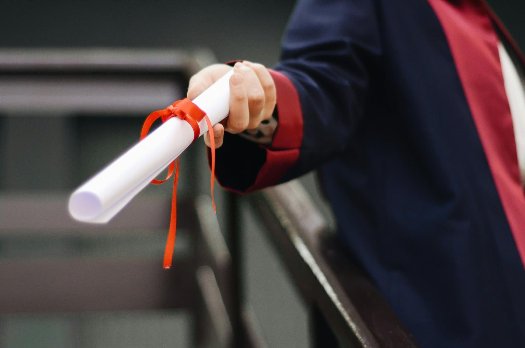 Student wearing graduation robes, while handing out his diploma