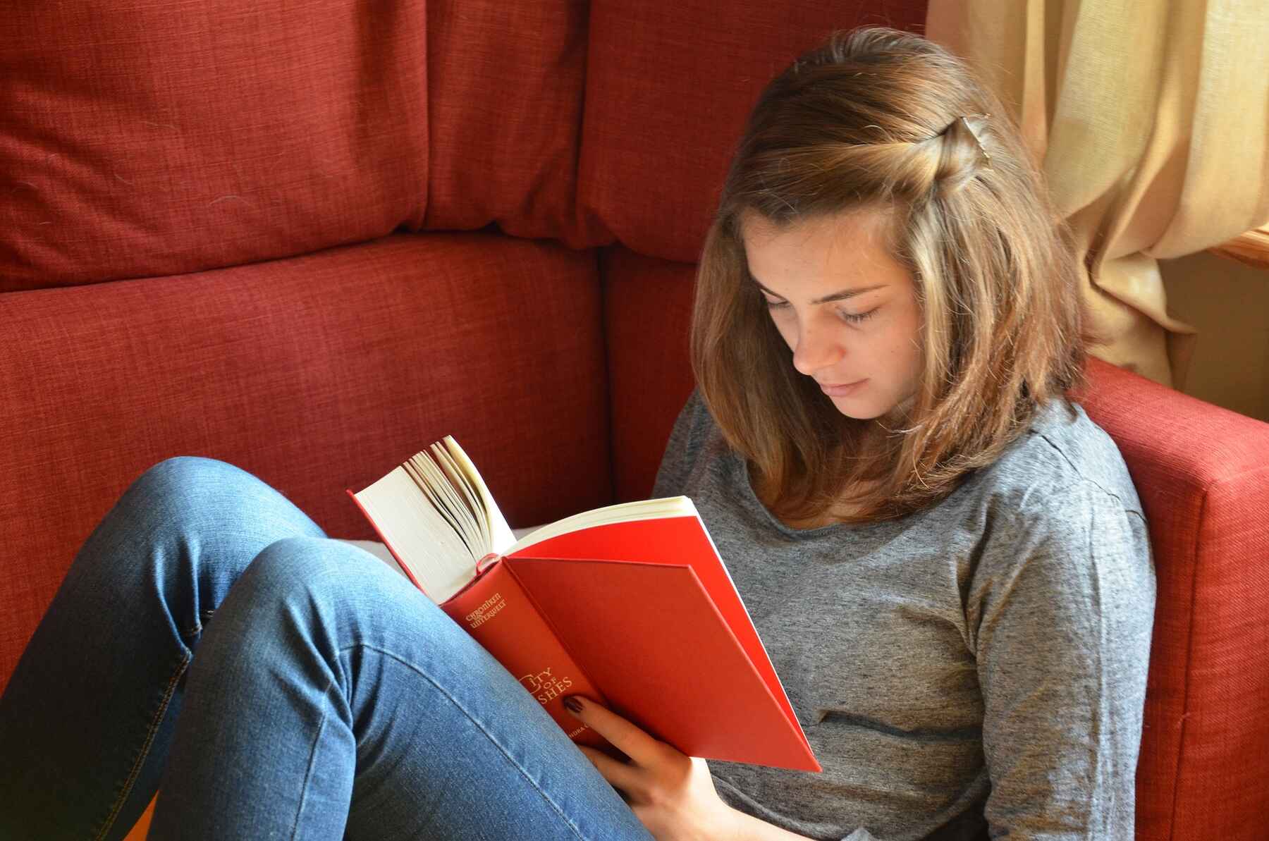 Woman sitting on a couch while reading a book
