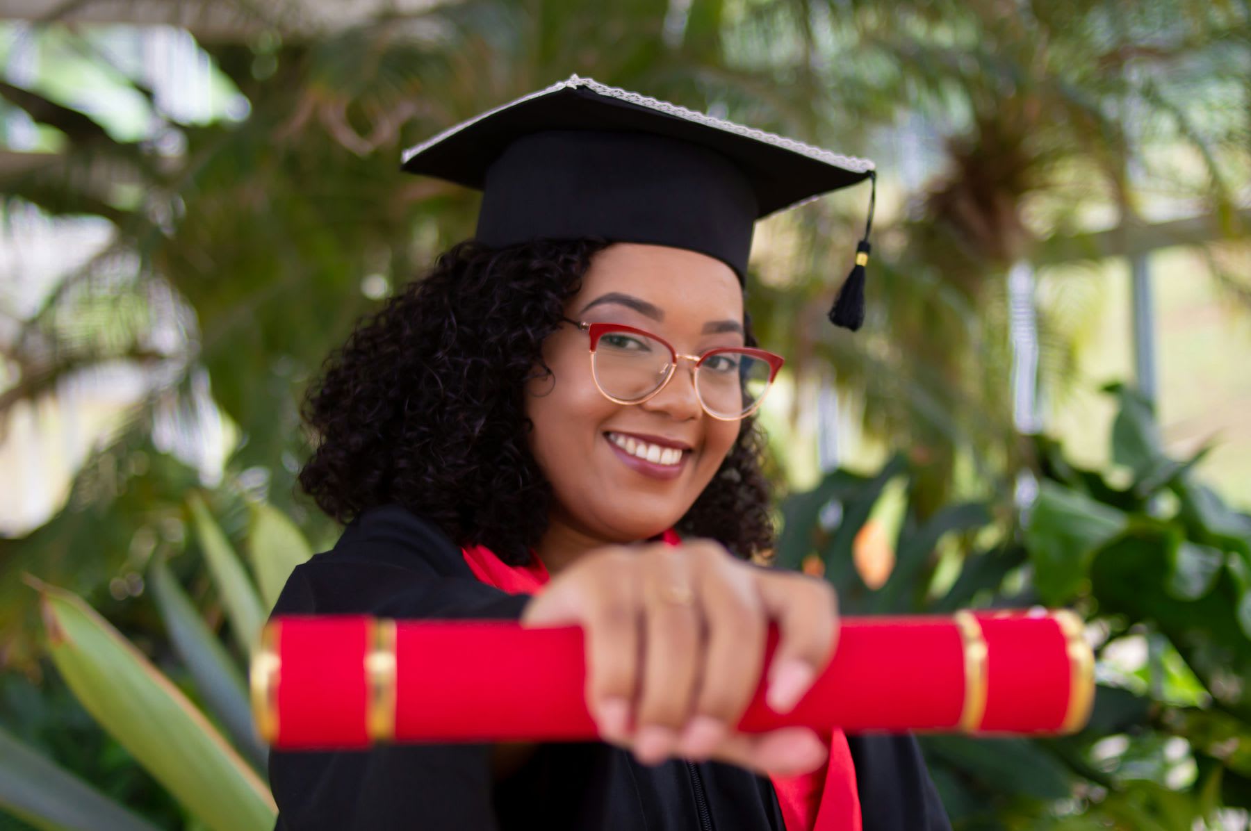 Woman wearing graduation robes and caps showing off her graduation scroll