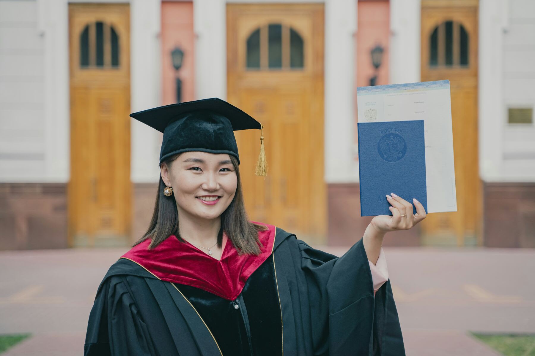 Woman wearing graduation robes while holding a diploma