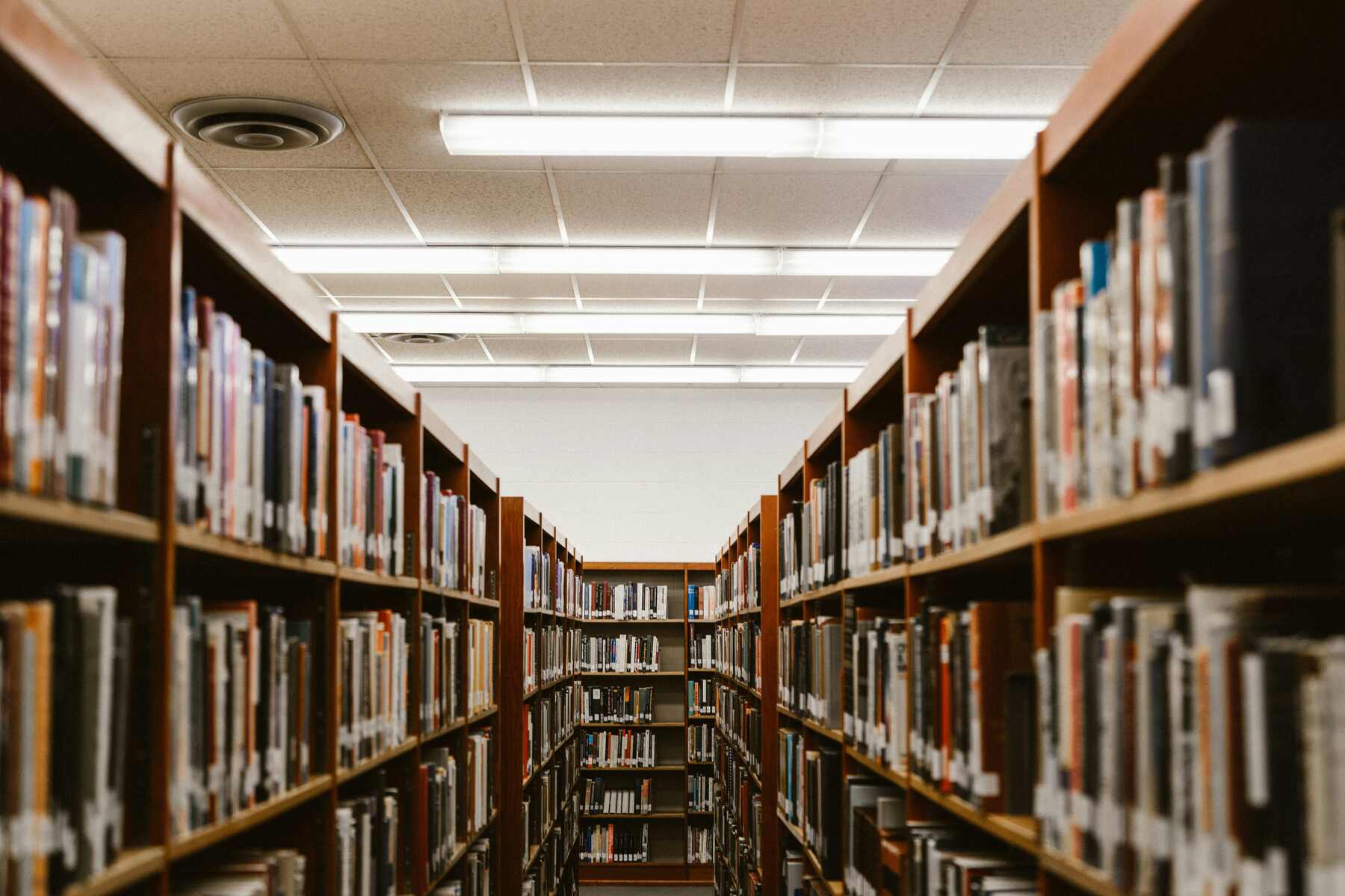 A narrow aisle of books filling the shelves in a library