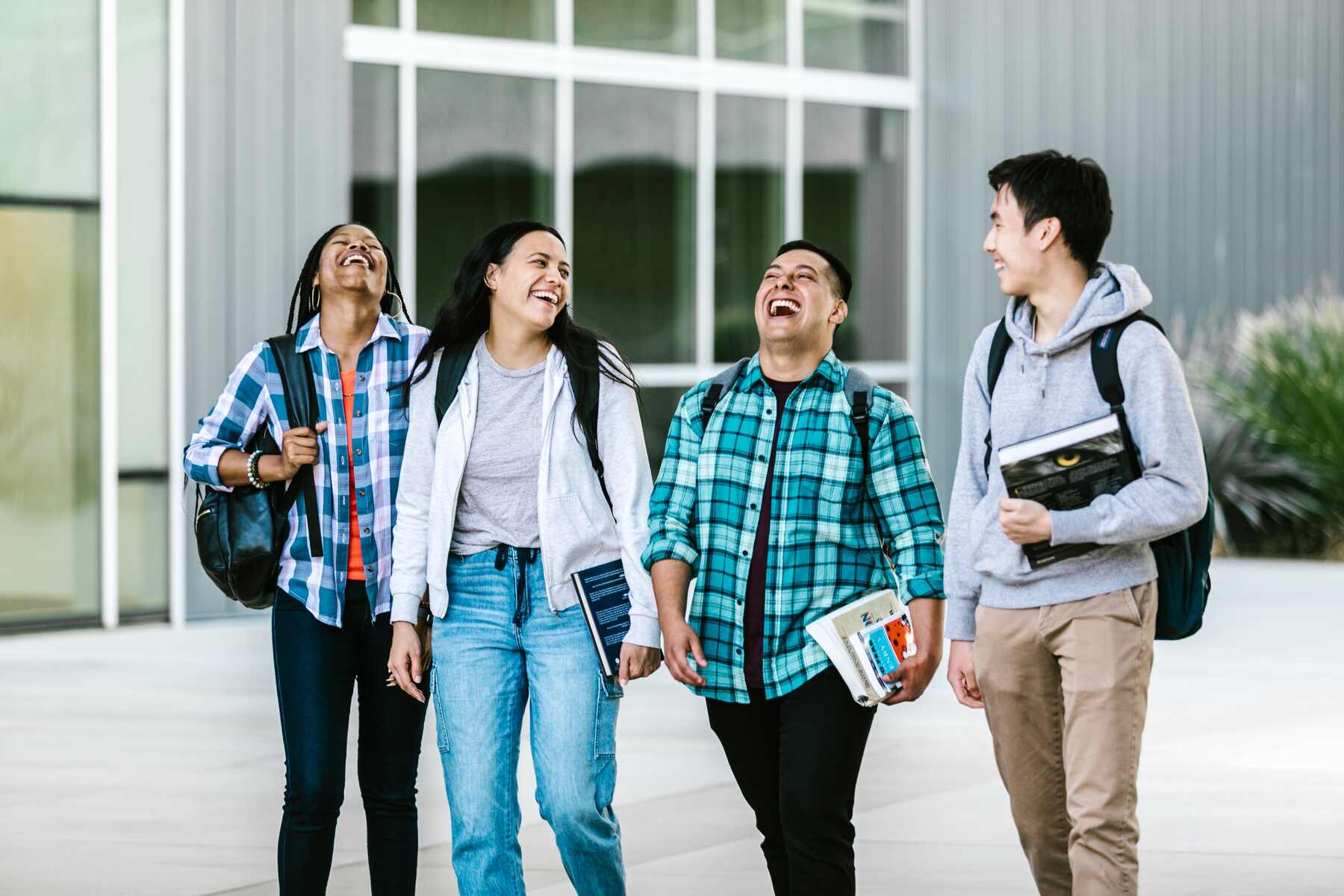 Group of students laughing and walking together on school grounds