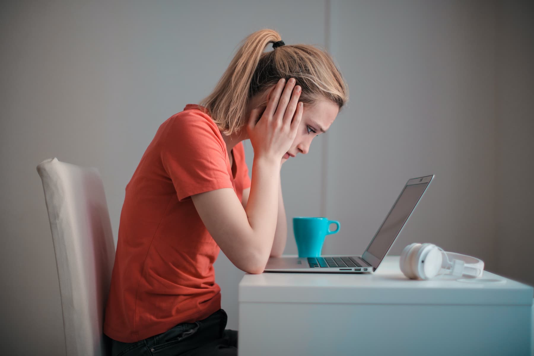 Woman with her hands on her face, starting intently at her laptop screen