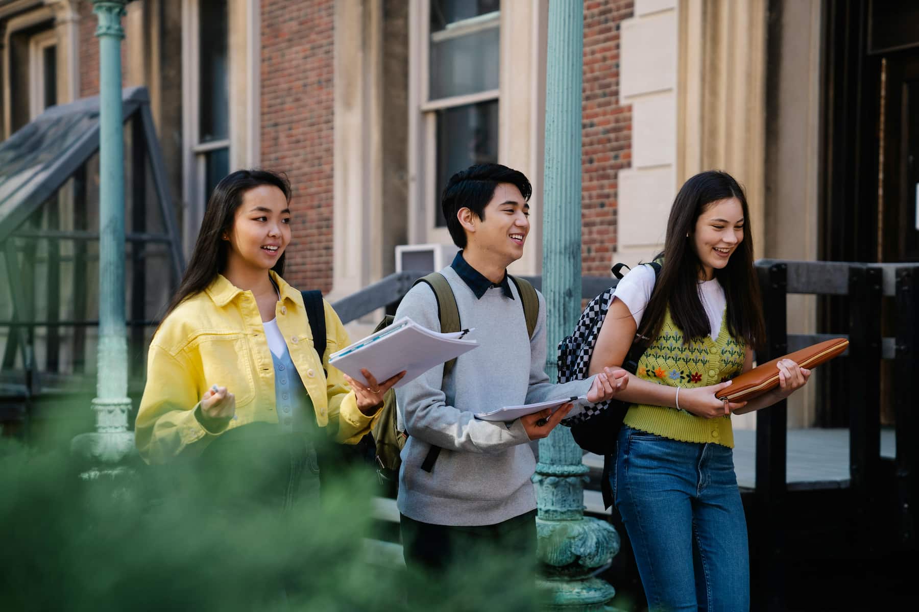 Three students carrying books and notes while on their way to their class