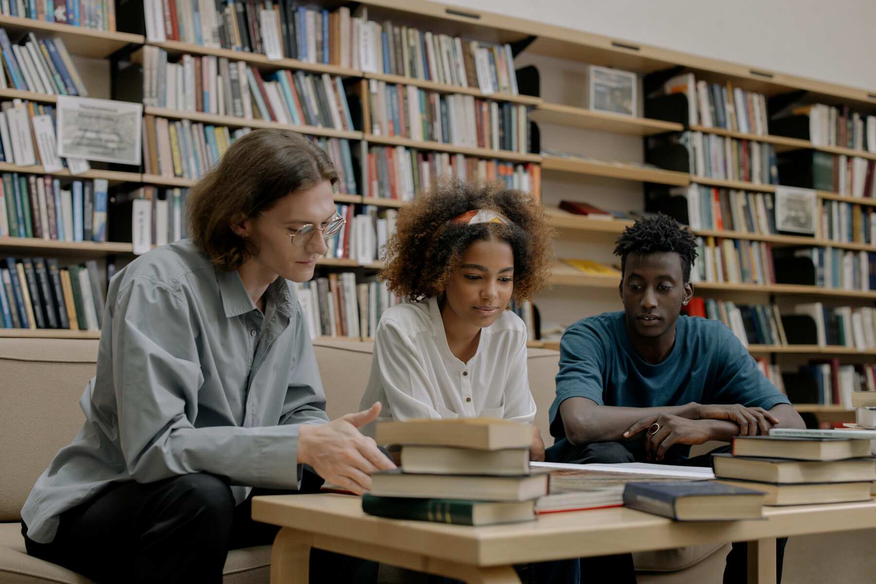 Three students filtering through a pile of books on their table