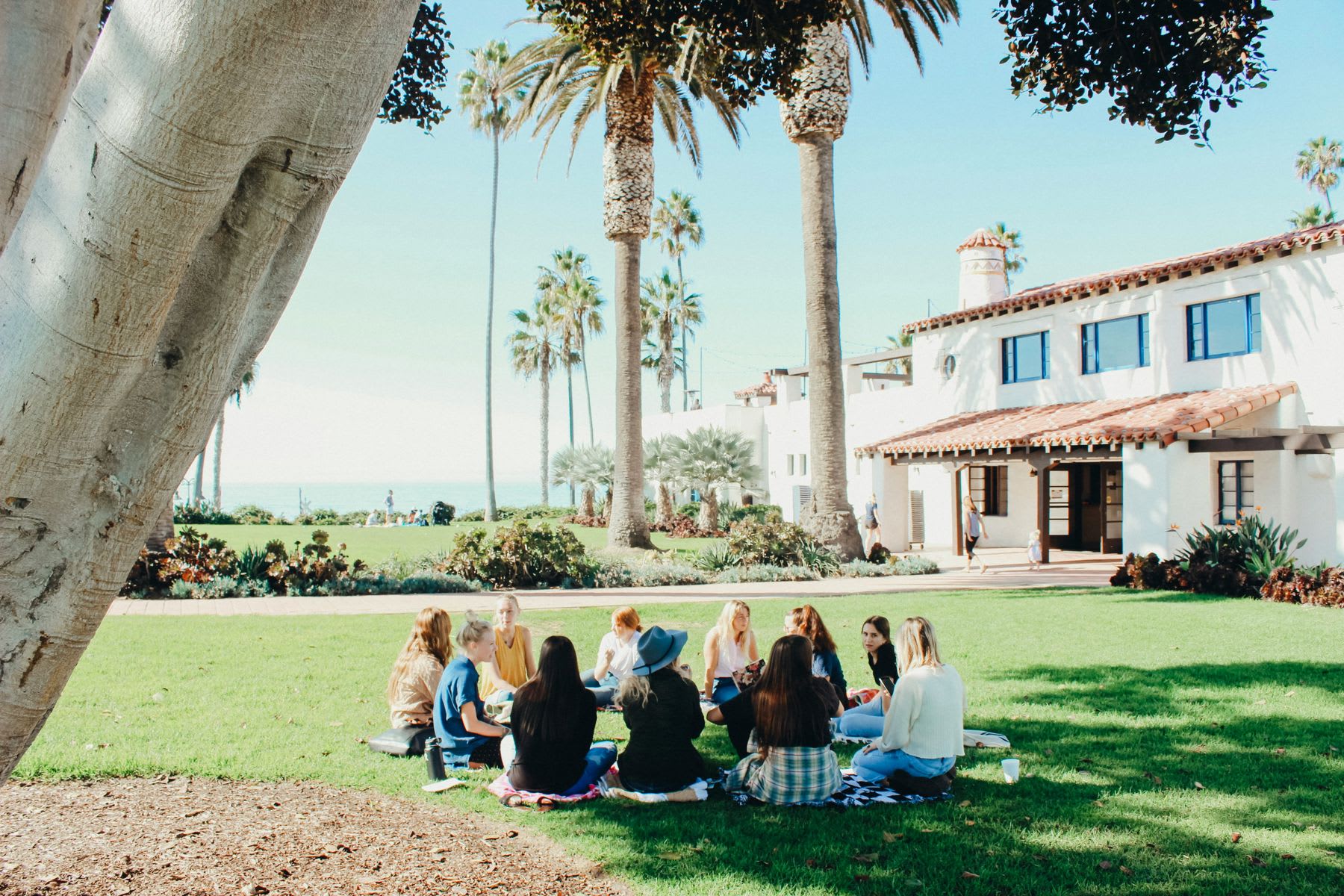 Group of students sitting in a circle on a campus lawn