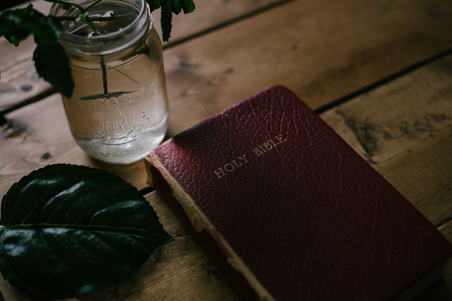 Holy bible and a jar with flower placed on the table