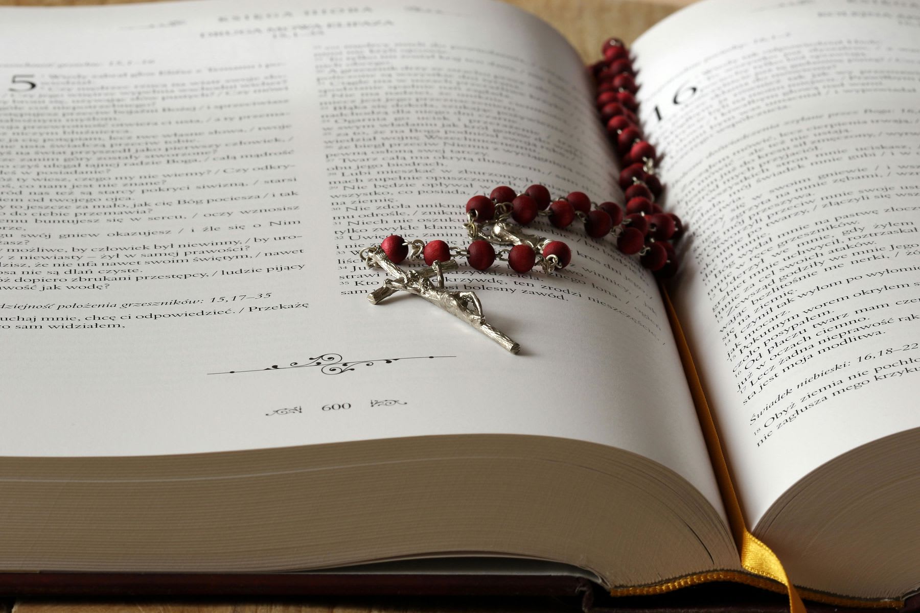 Rosary in between the pages of an opened Bible