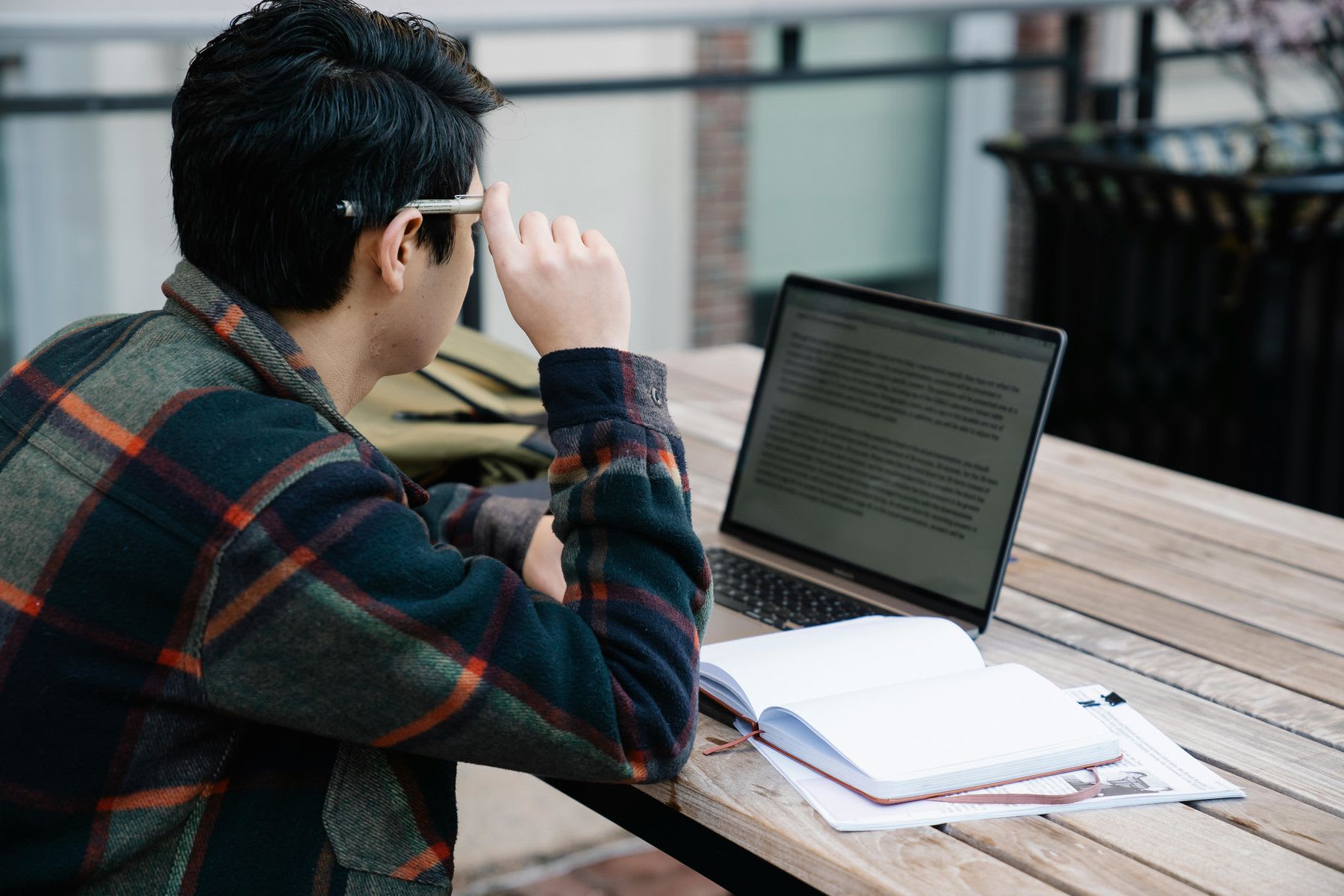 Man adjusting his glasses as he reads a text discourse on his laptop