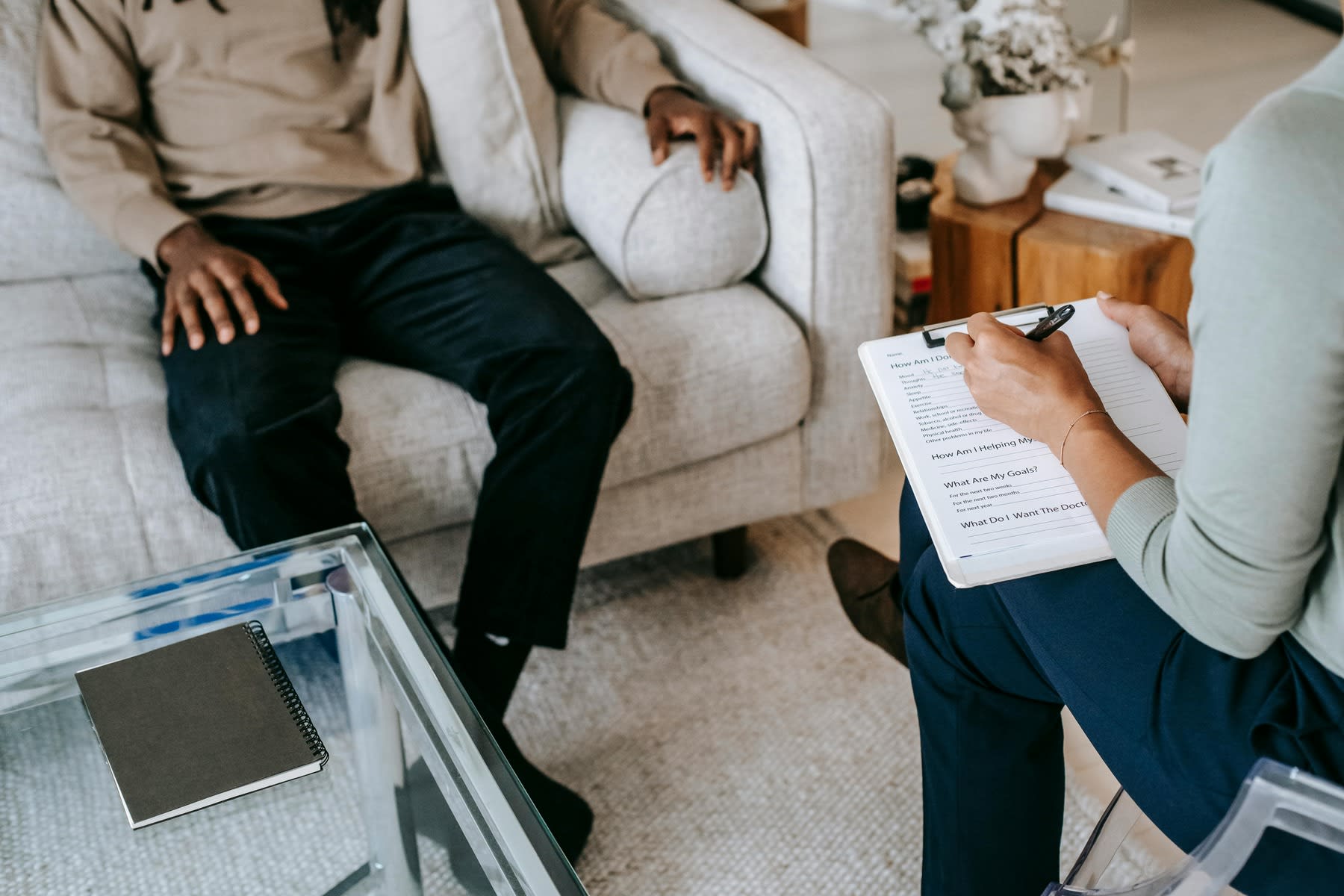 Woman writing down notes as she talks to her patient during a therapy session