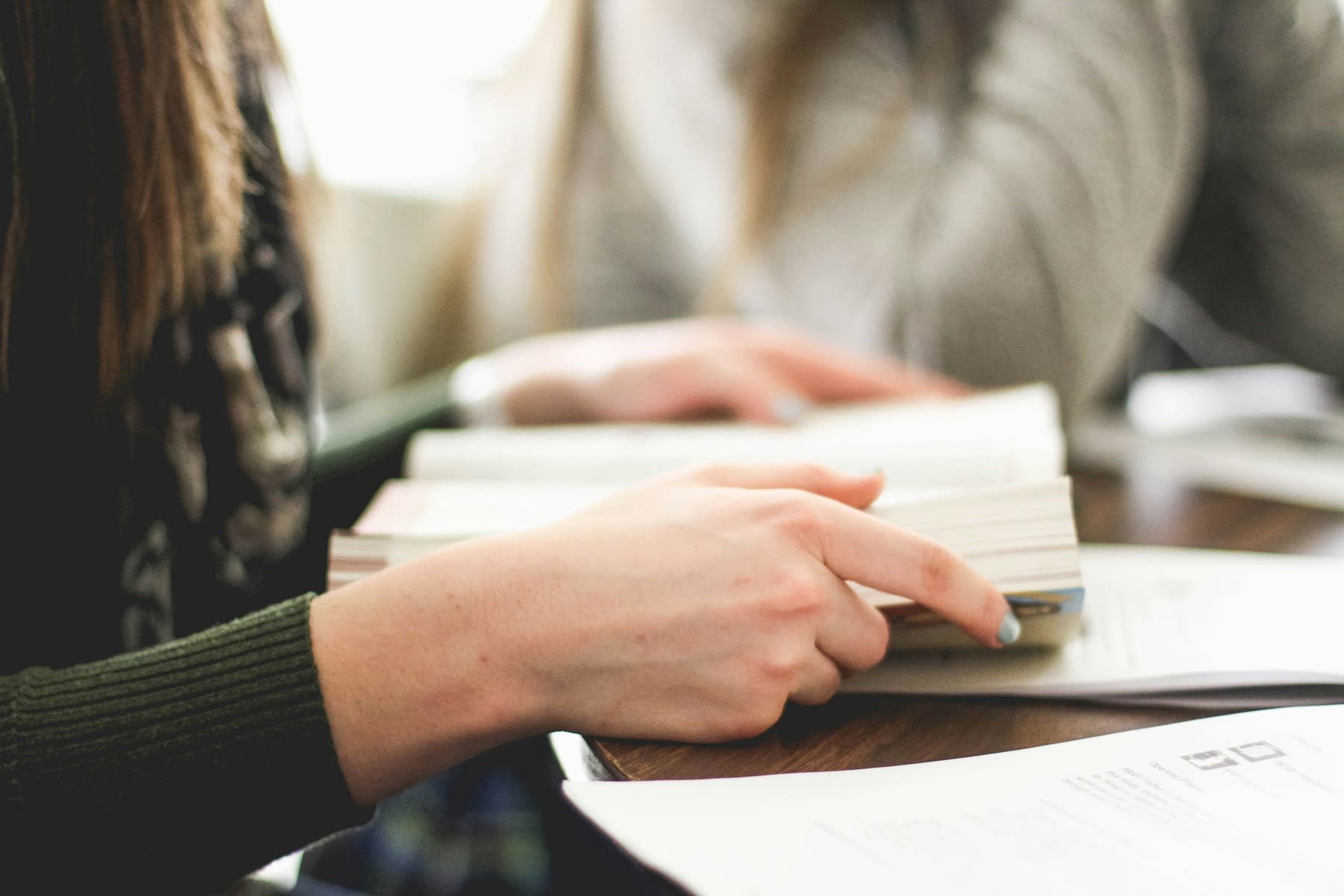 Woman reading a book while seated on a table
