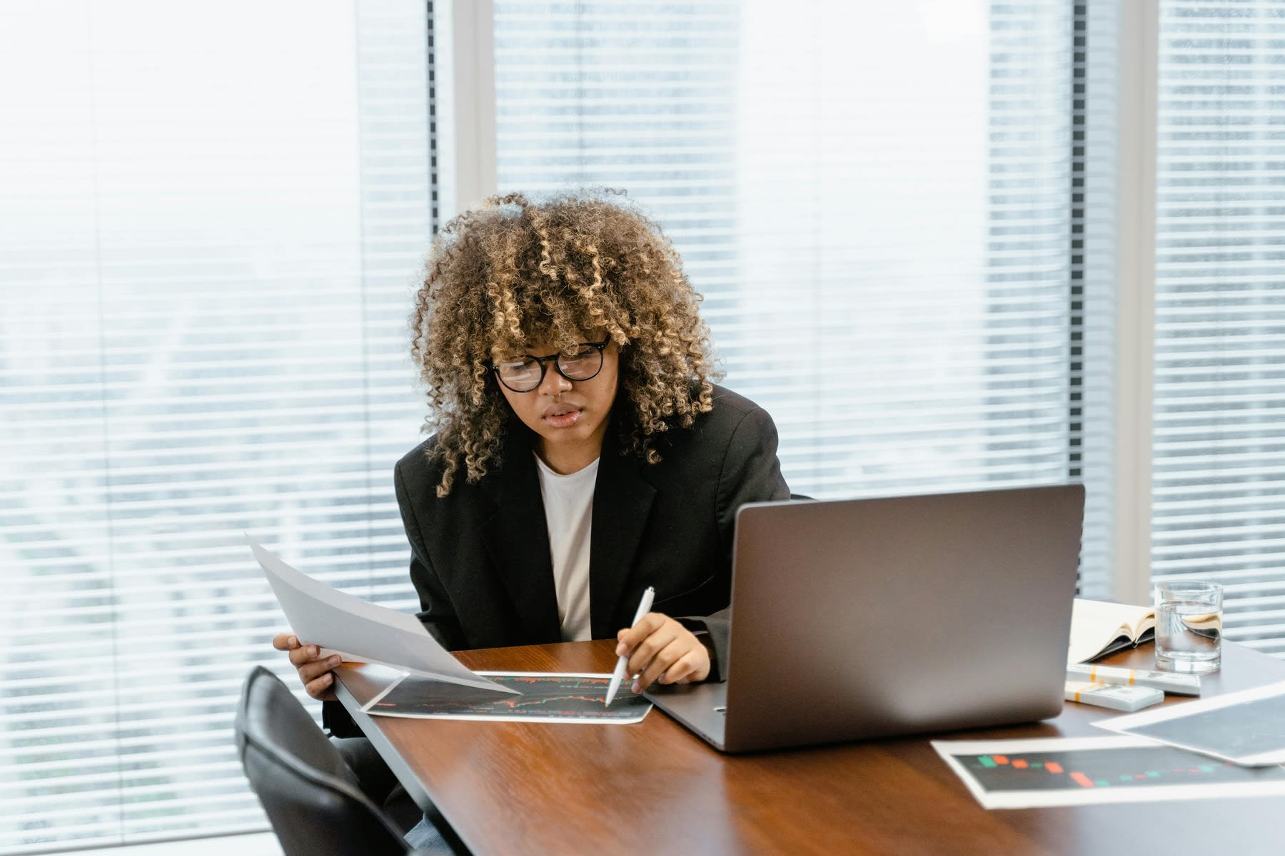 Woman looking at printed reports while taking notes with her pen