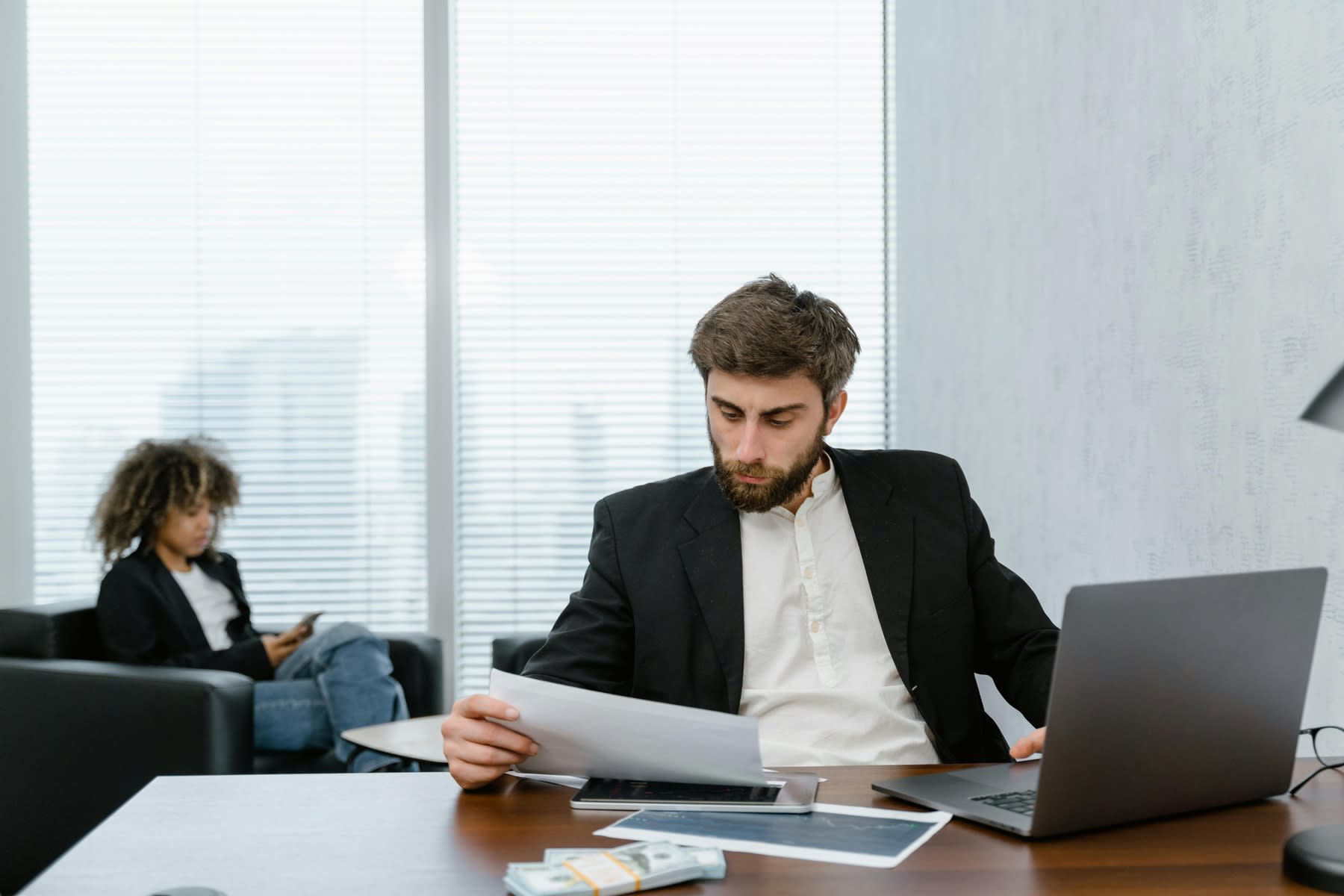 Man looking at a printed report while using a laptop