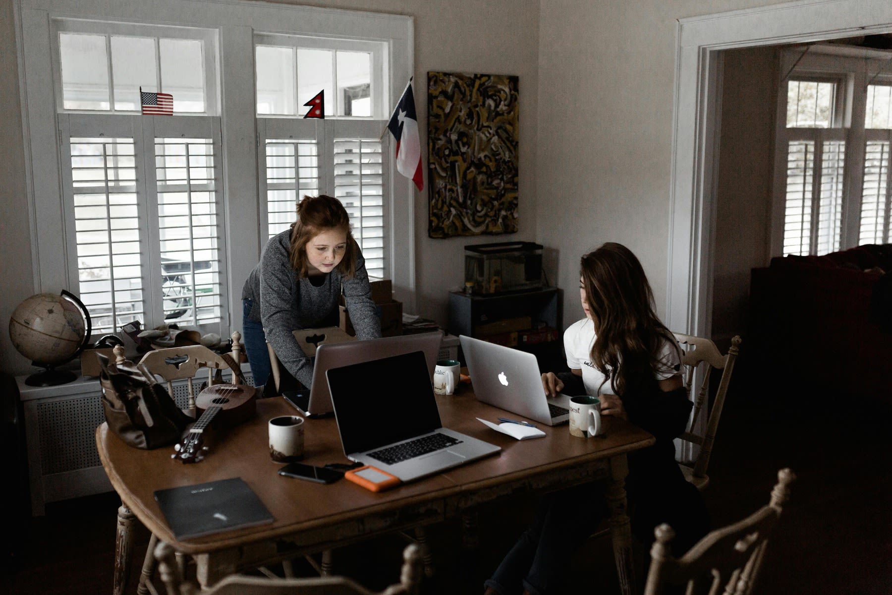 Two people working on a single table with their laptops