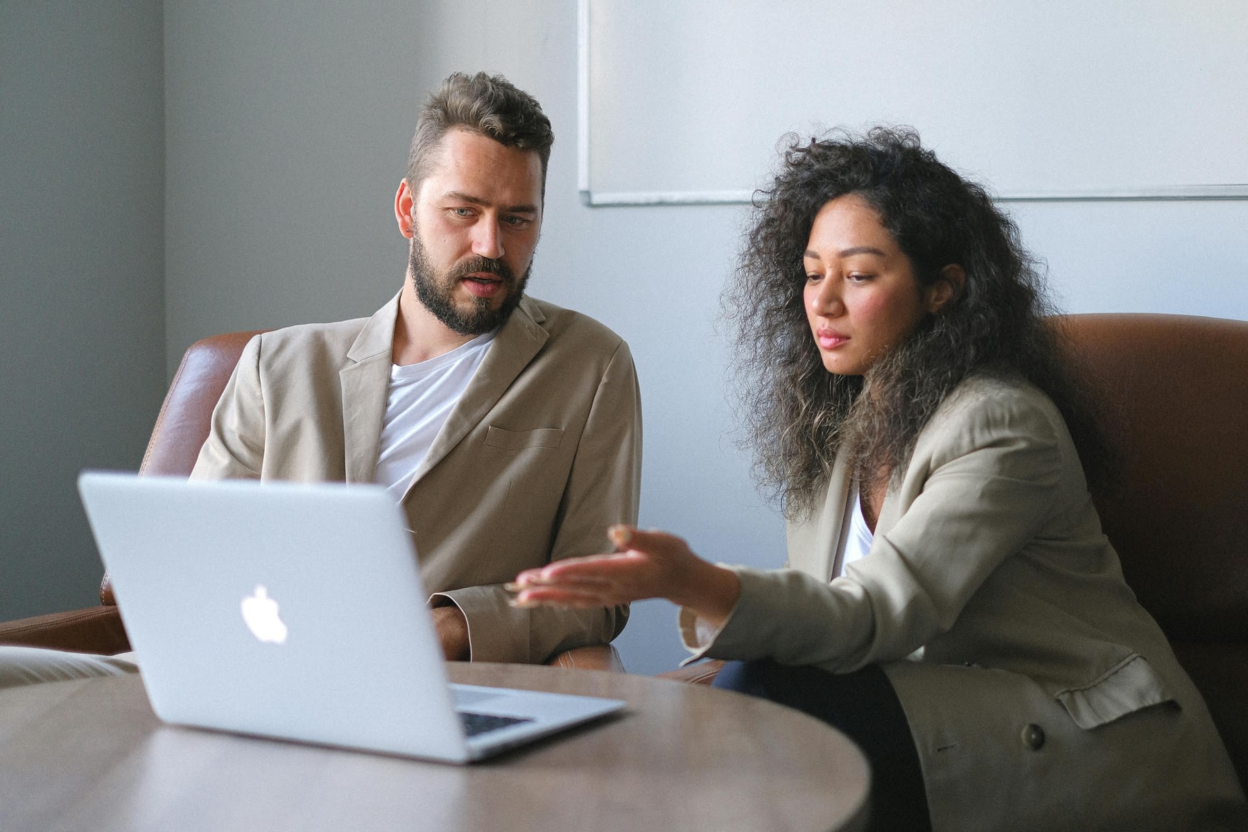 Woman pointing something on the laptop screen to her partner during a meeting