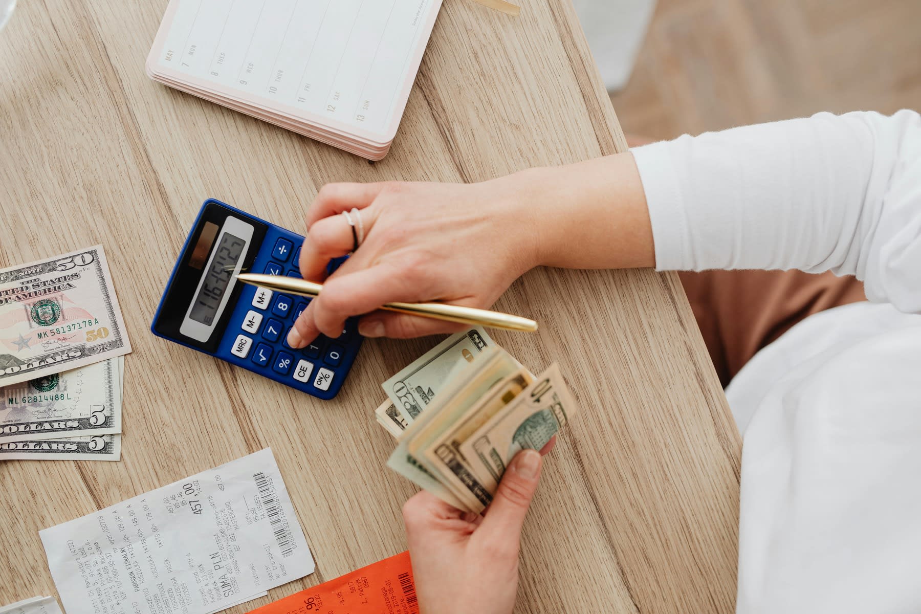 Woman using a calculator while counting dollar bills