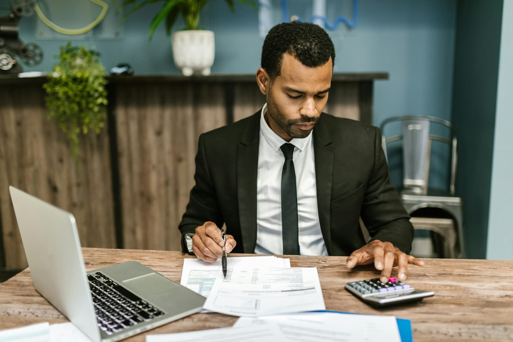 Man using a calculator while reviewing printed reports