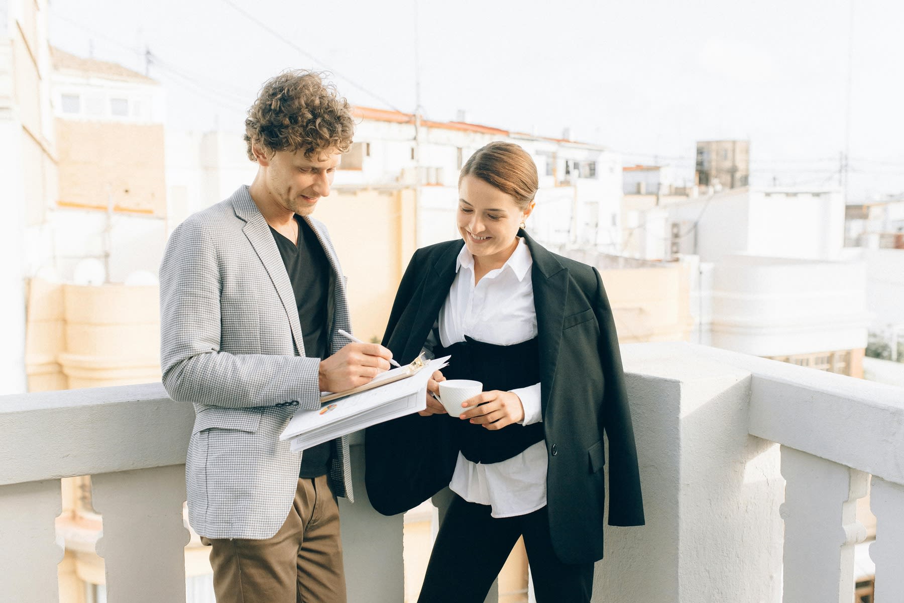 Man writing down notes on a printed paper while a woman standing beside her looks on