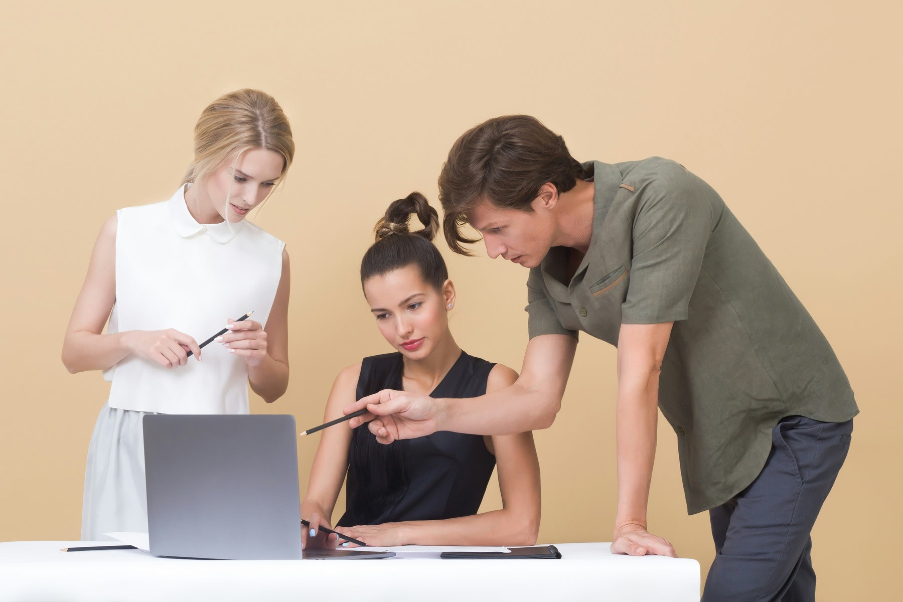 Two people hovering around the company consultant's laptop and desk