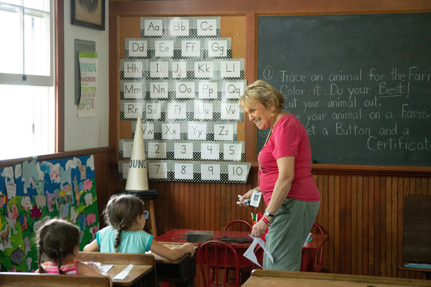 Female teacher walking close to a young student's desk during class