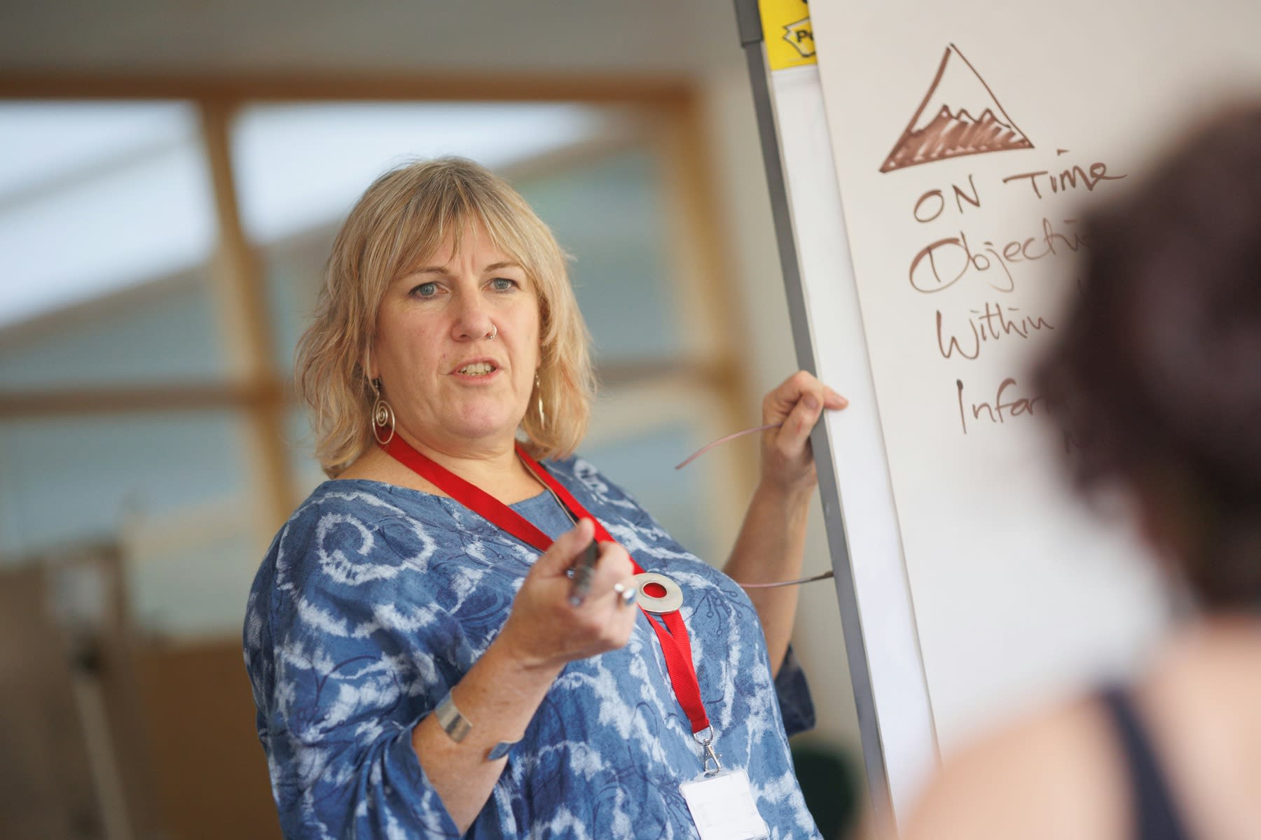 Woman writing on a white board while leading a presentation