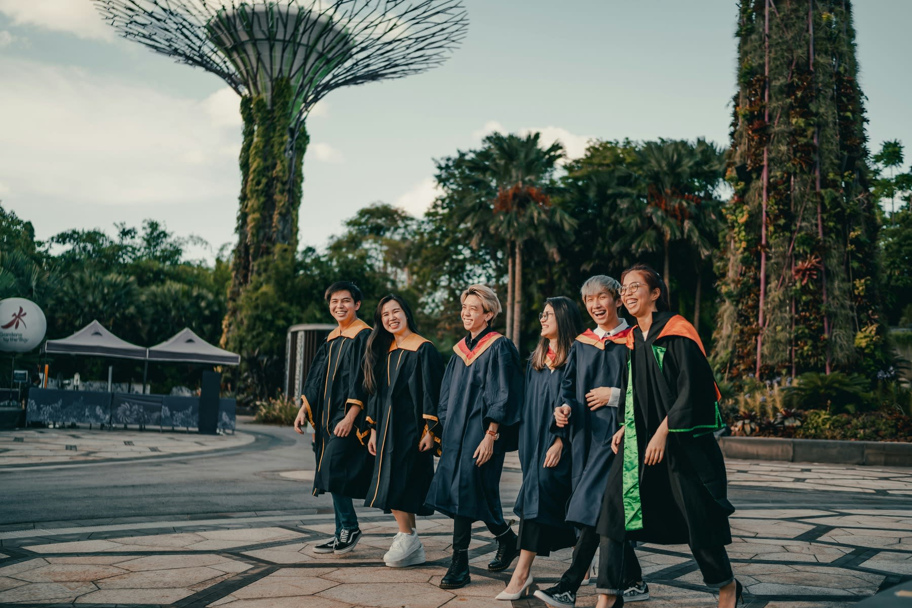 Students wearing graduation robes while walking together on campus grounds