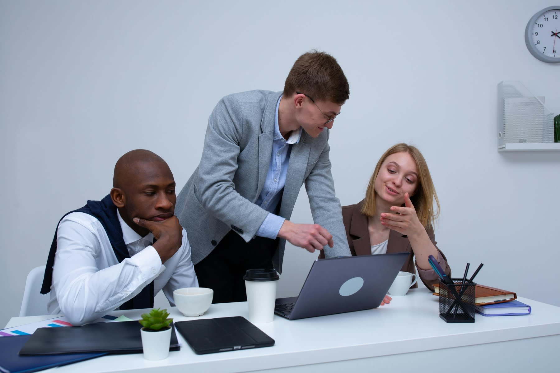 Employees looking at the same laptop, while working together on a project