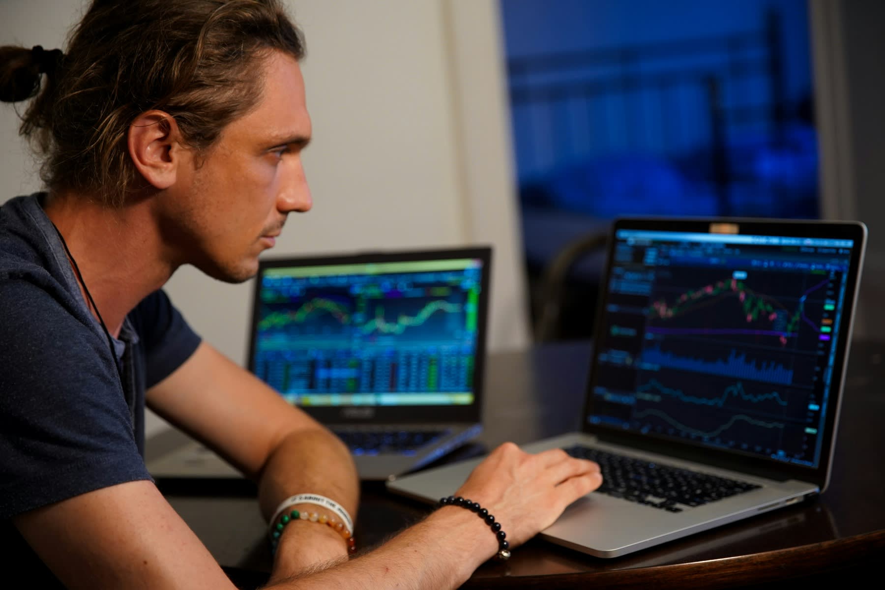 Man looking at data analytics on multiple laptops