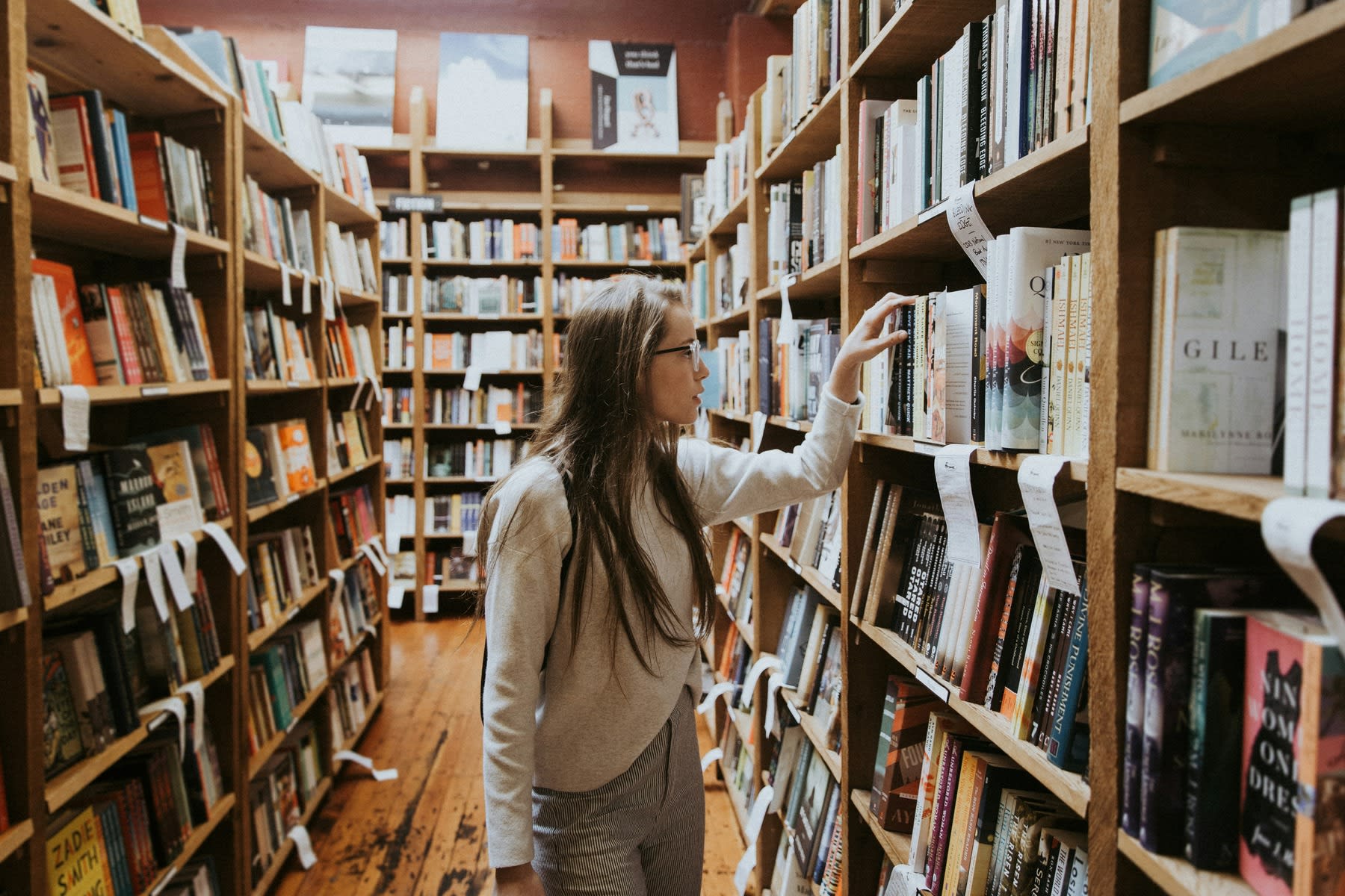 Woman grabbing a book from a book shelf