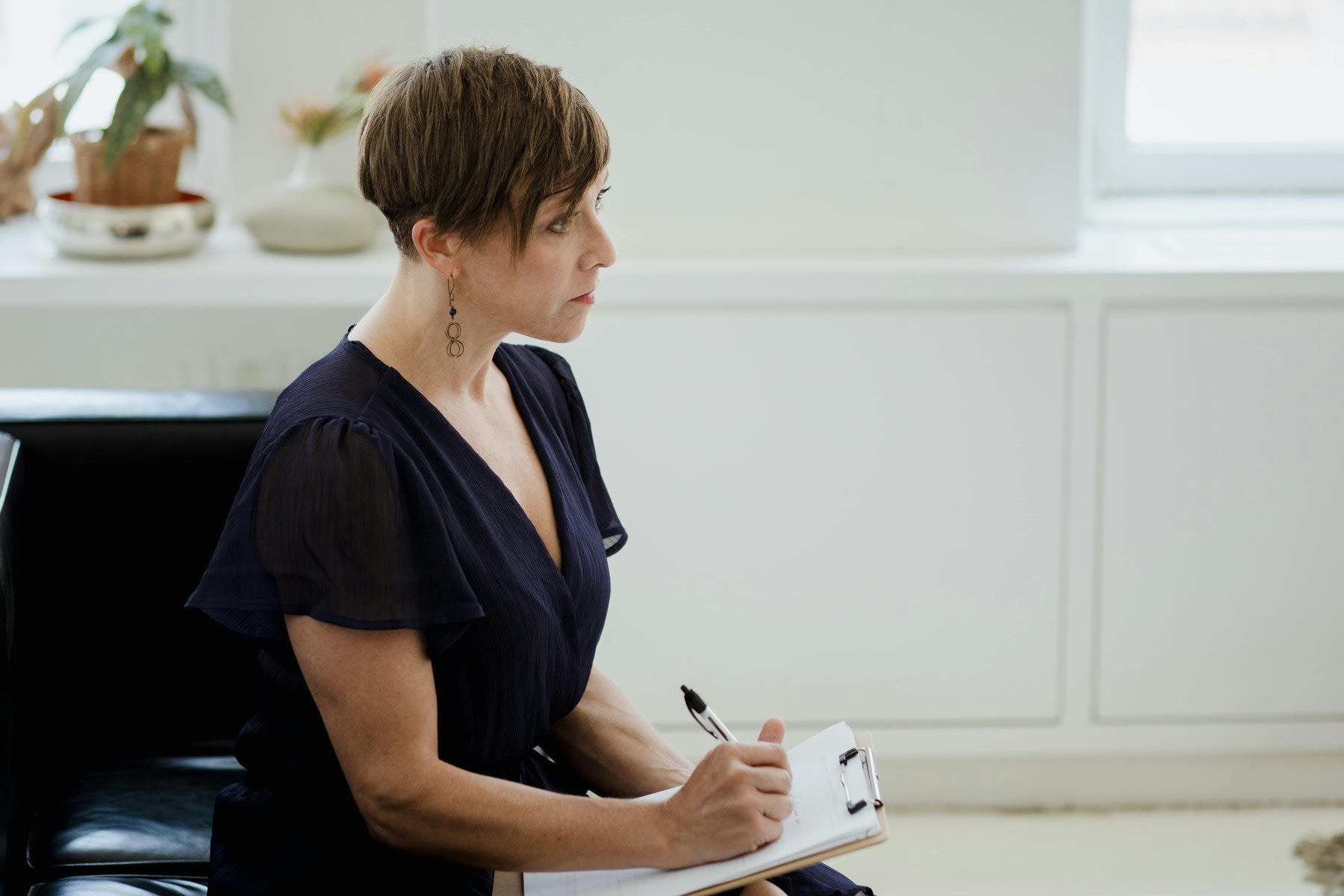 Therapist writing down notes on her clipboard during a session