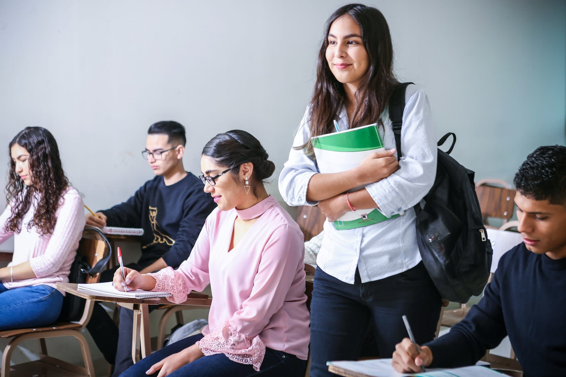 Woman carrying a backpack while holding on to her books as she makes her way to her class