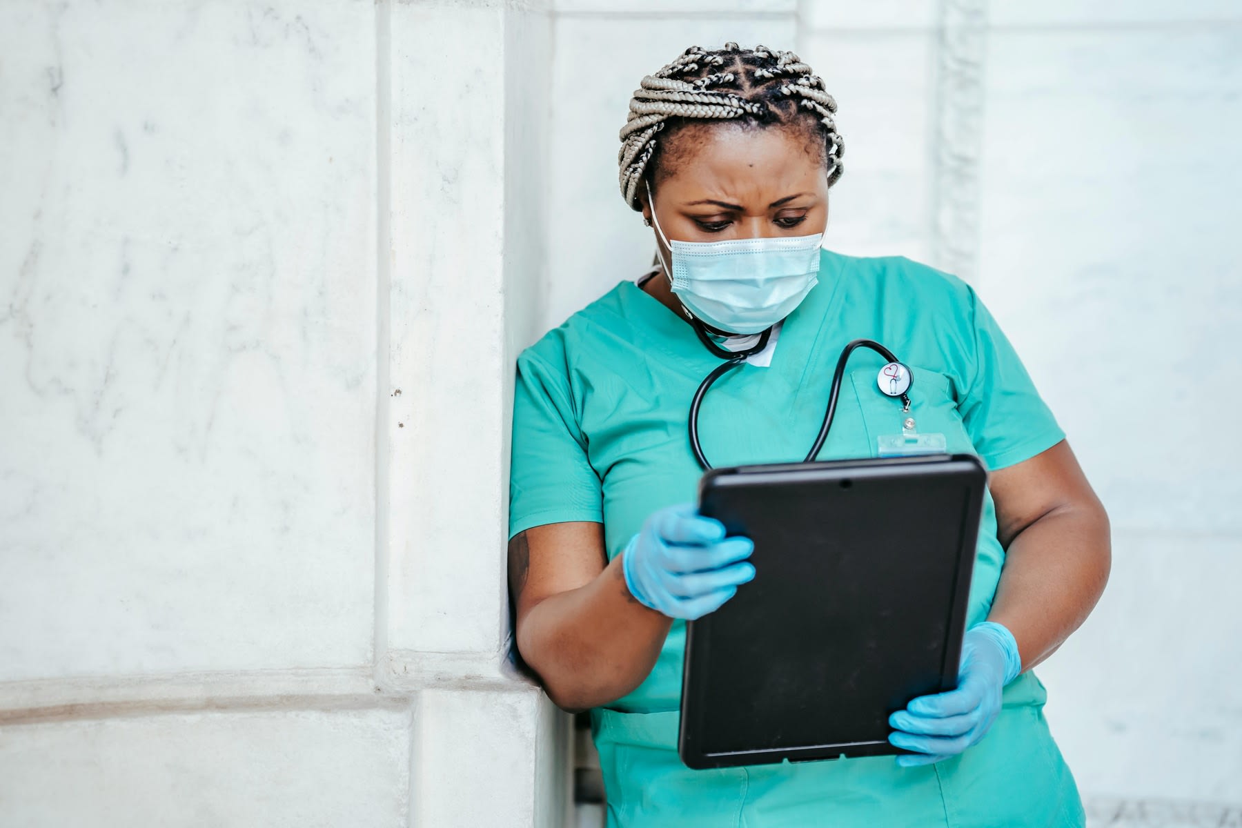 Nurse with gloved hands looking at her tablet