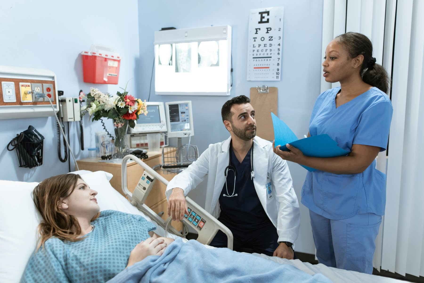 Doctor and patient listening to a nurse as she updates the patient about her condition