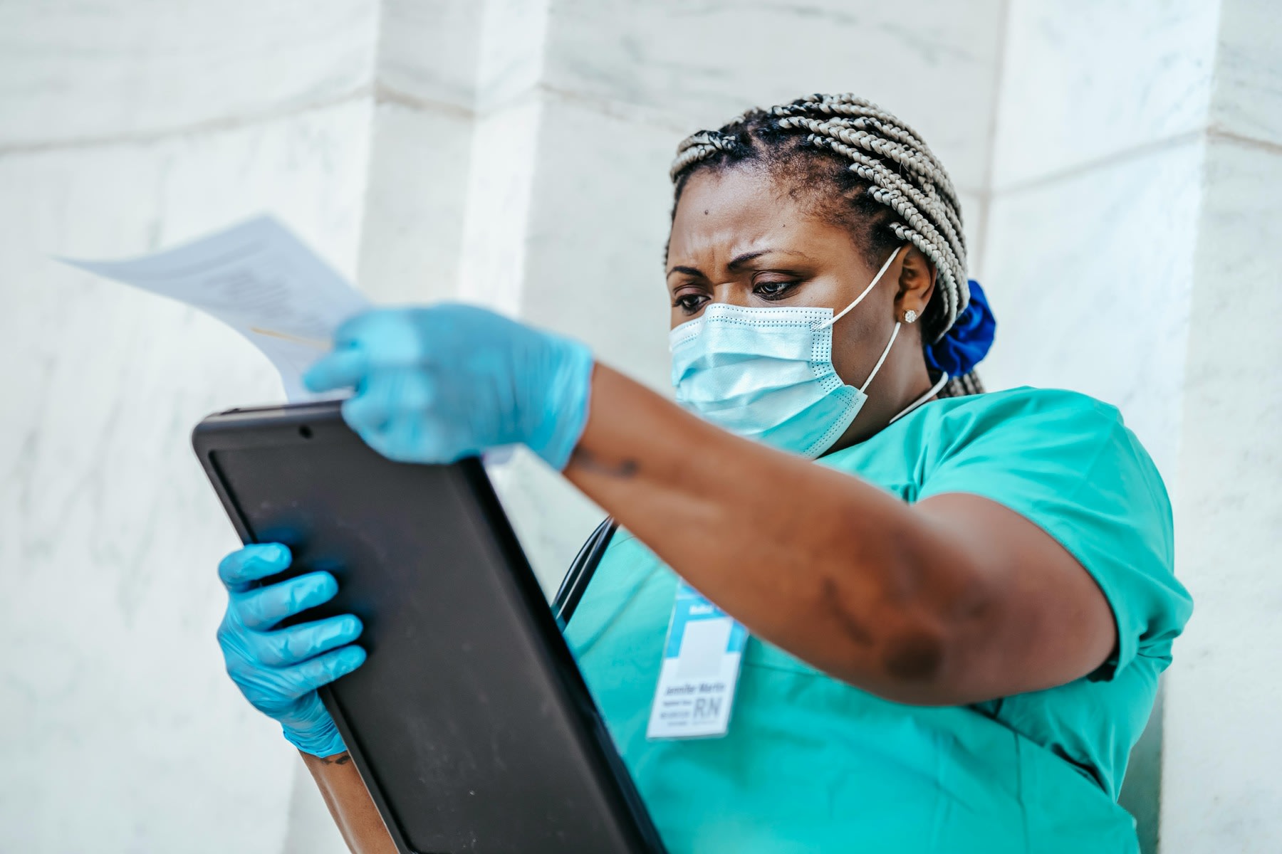 Nurse with gloved hands checking her clipboard