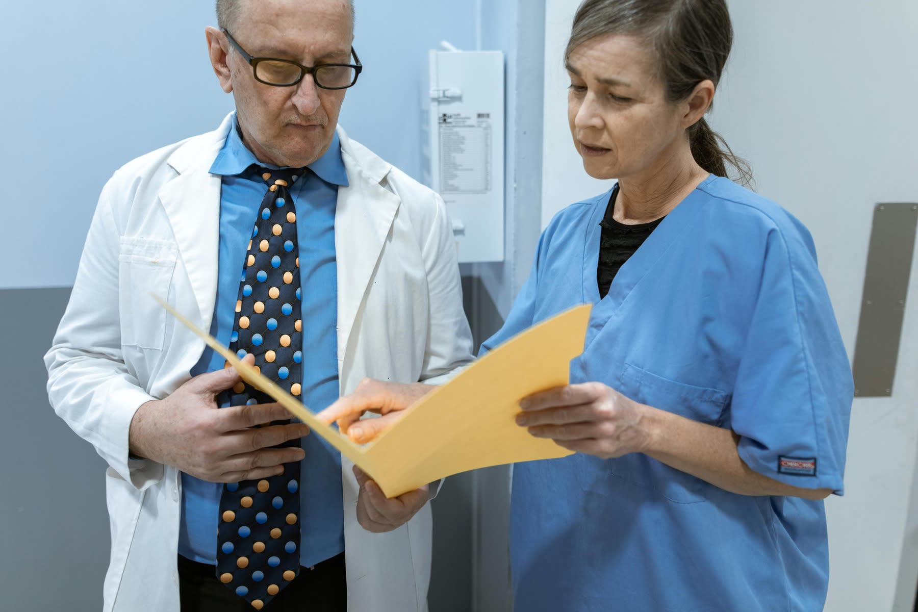 Nurse showing a file folder to a doctor