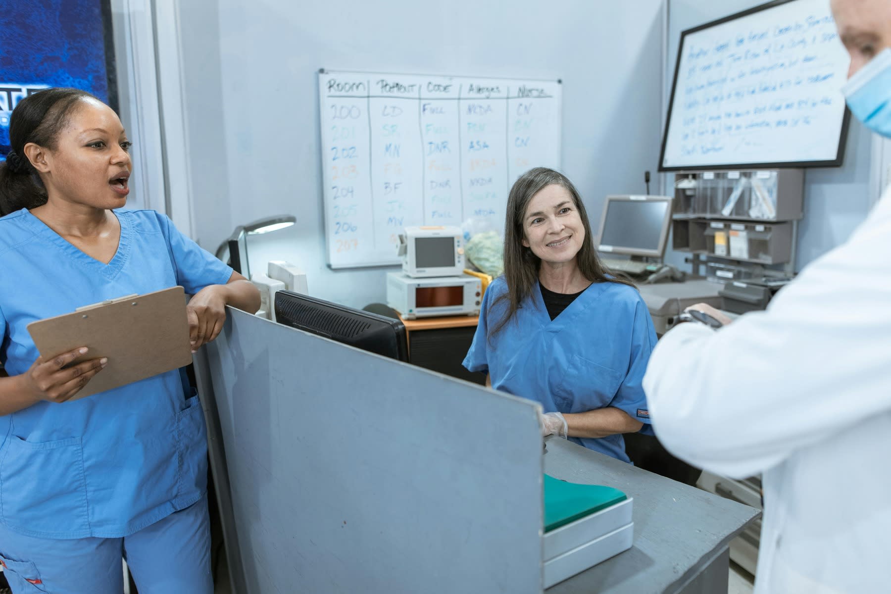 Two nurses looking at a doctor