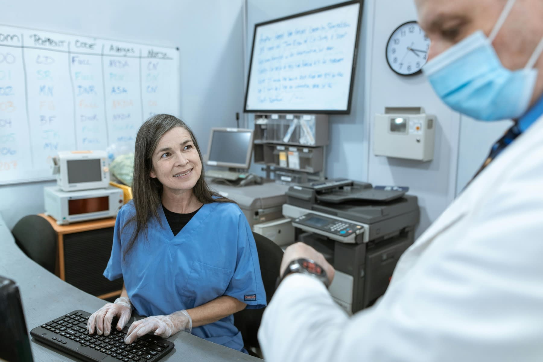 Nurse typing on a keyboard while talking to a doctor